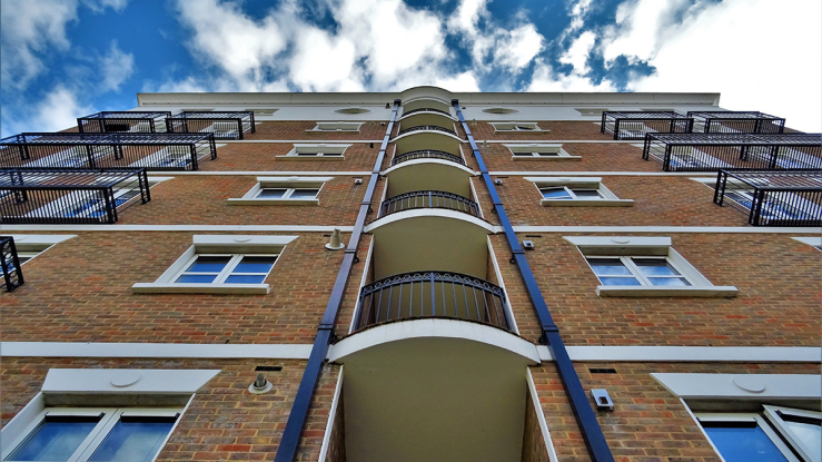 View looking up the face of an apartment building, towards the sky.