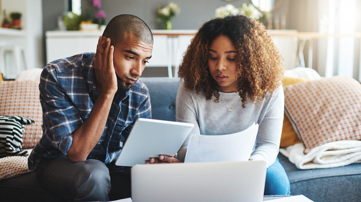Couple considering bills in living room.