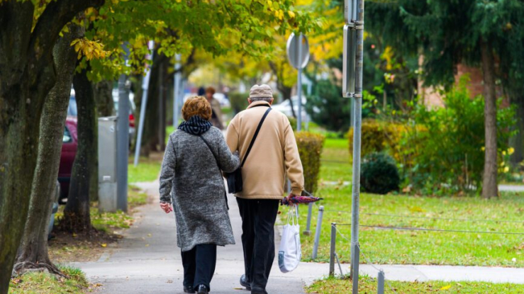 Older couple walking down sidewalk.