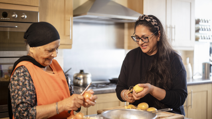 Older and younger woman cooking together in a kitchen.