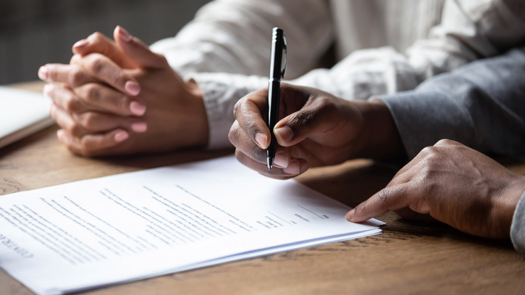 Two people signing homeownership documents.