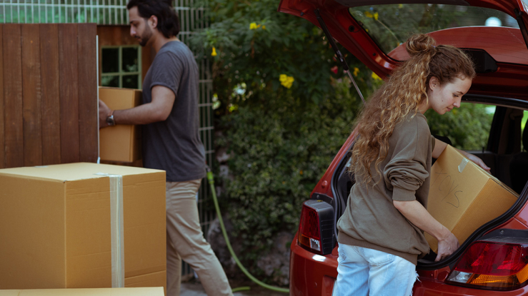 Young couple loading possessions into car.
