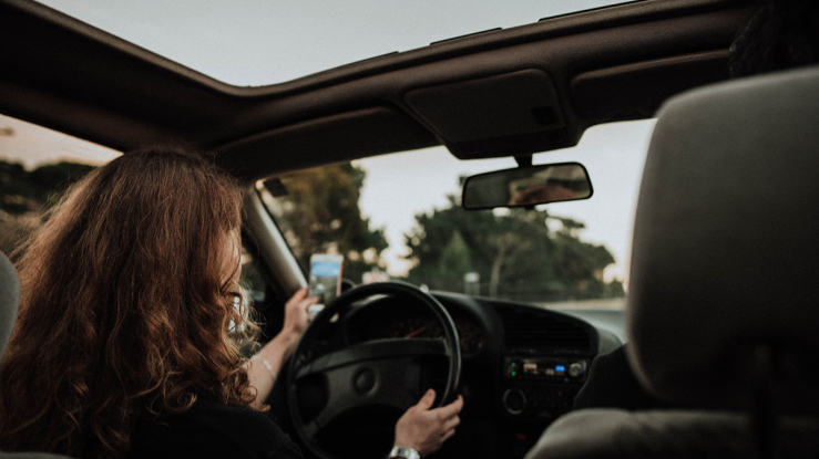 Woman driving a car and looking at her cell phone