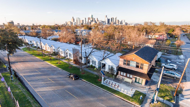 Aerial view of row houses with city skyline behind them