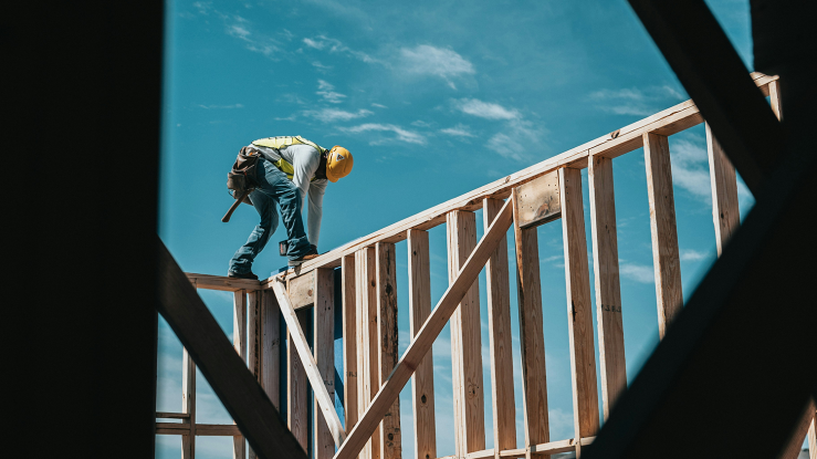 Man in hard hat working on top of wall.