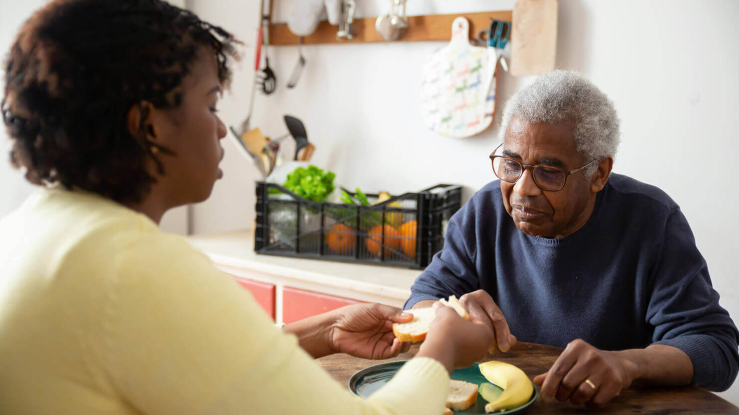 Man having a meal at home with a caregiver.