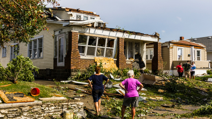 People outside a damaged home.