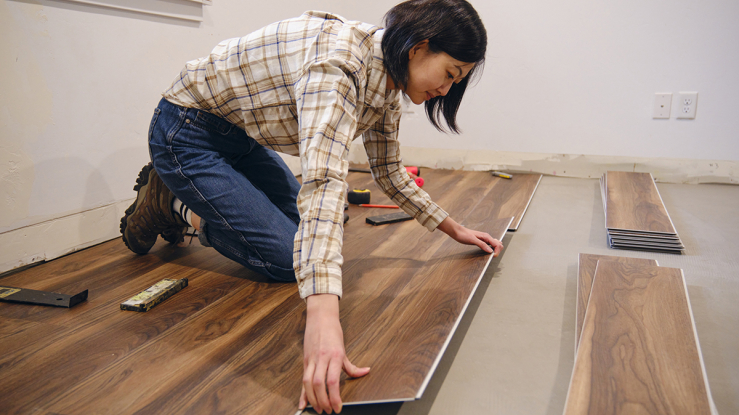 Asian woman installing click flooring
