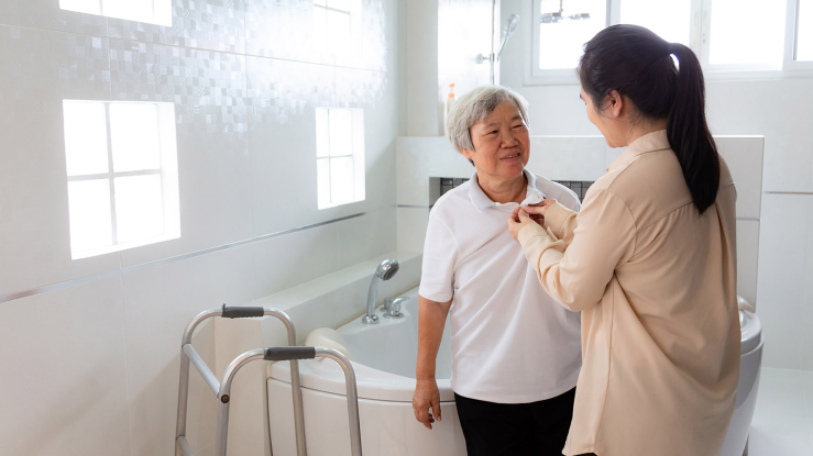 Caregiver helping older adult get dressed.
