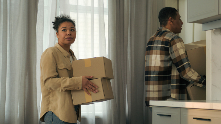 Two people moving boxes out of a home.