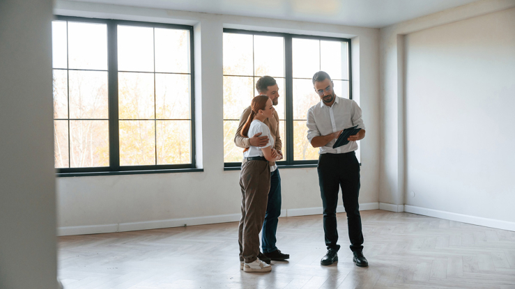 Young couple with a realtor in an empty home.