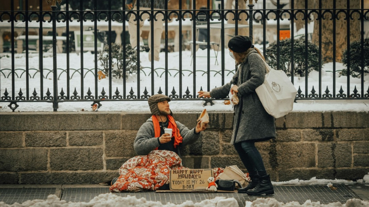 Person handing food to person on sidewalk.
