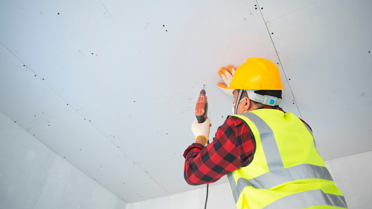 Worker installing drywall in a home.