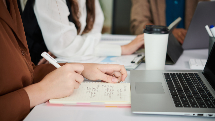 Students taking notes at a conference room table.