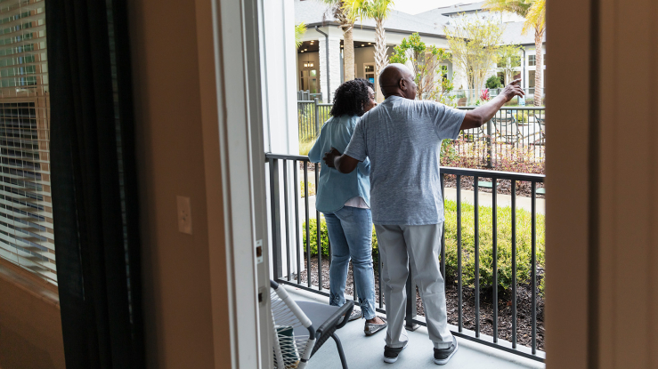 Older adult couple outdoors on apartment patio.