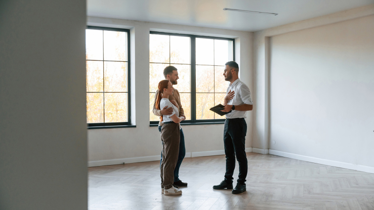 Couple standing in empty apartment with realtor.