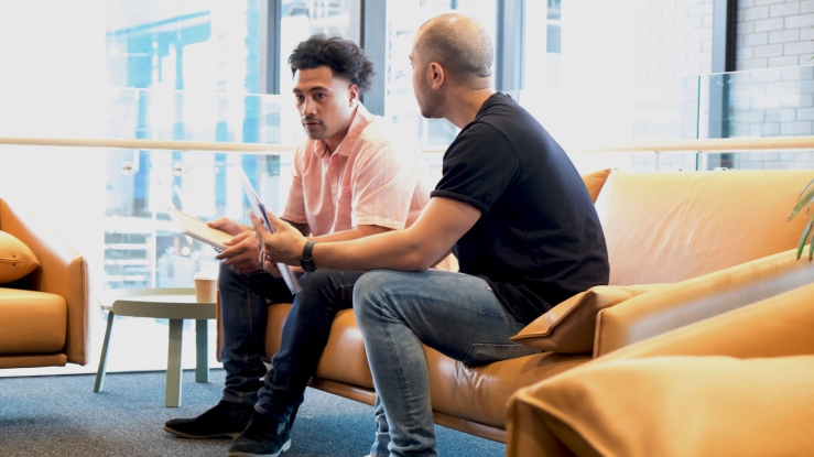 Two young men sitting in an office reception area.
