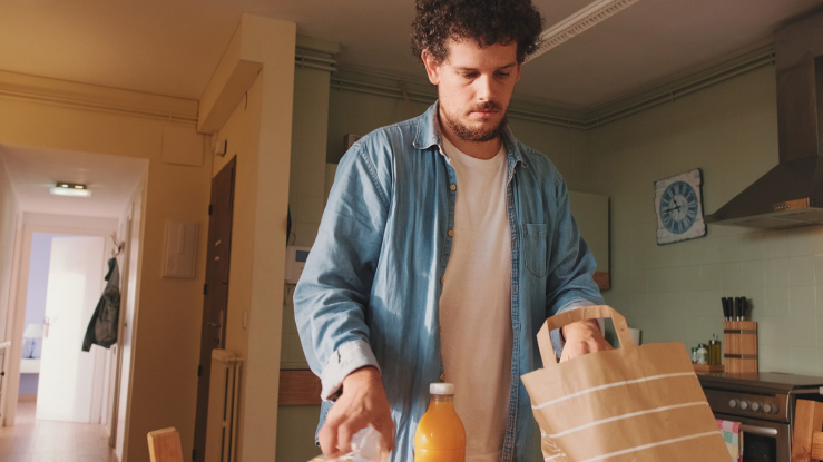Man unpacking groceries in apartment kitchen.