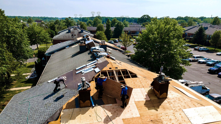 Workers installing roofing on a multifamily building.