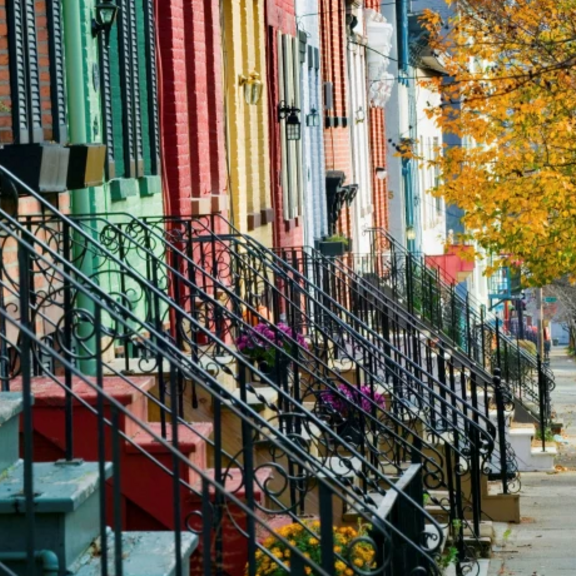 Row of townhouses with front staircases along street.