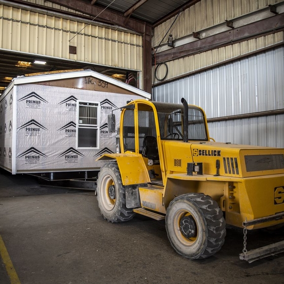 Tractor towing manufactured housing unit.