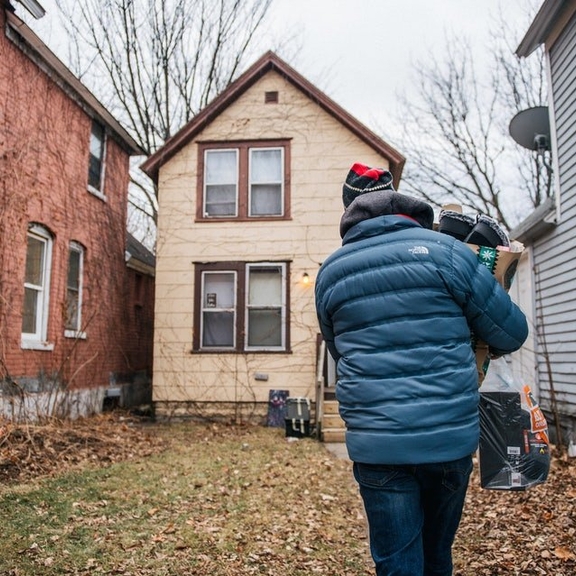 A man carries a bag of gifts to a home in St. Paul, Minnesota.