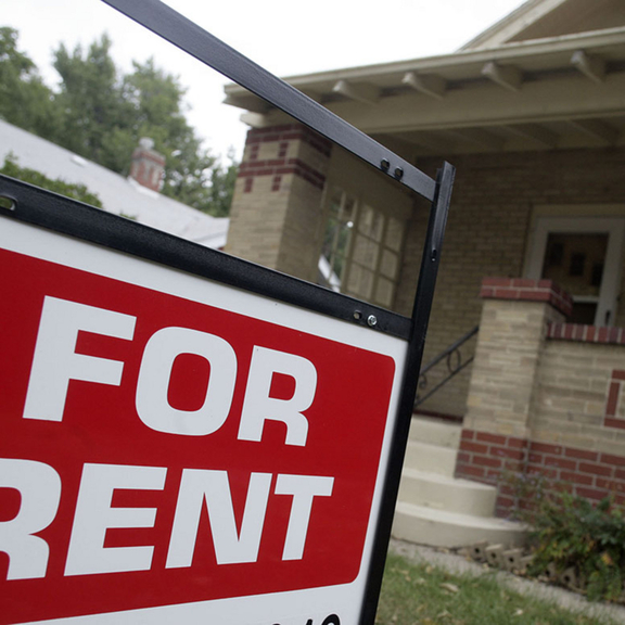 "For rent" sign in front of small home.