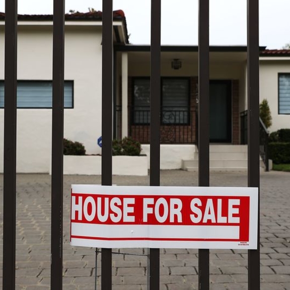 Home with gate and "house for sale" poster.