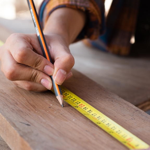 Person measuring board to cut it.