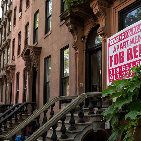 Row of townhouses with 'for rent' sign.