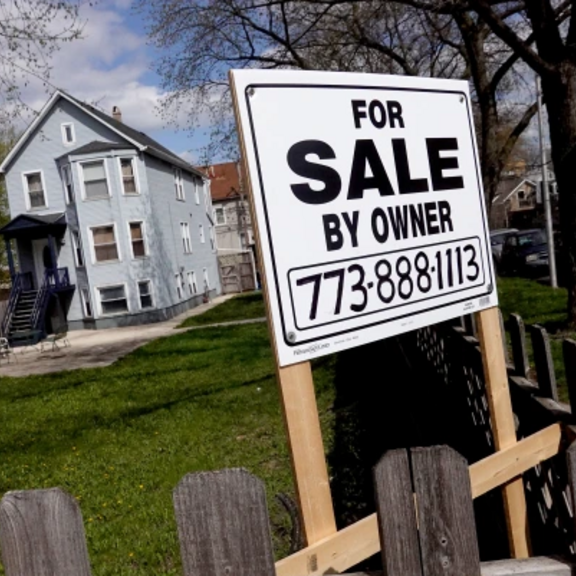 Sign saying "for sale by owner" in front of single-family house.