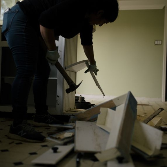 Person holding repair tools working on kitchen remodel.