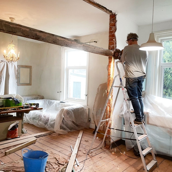 Man on ladder in apartment being renovated.