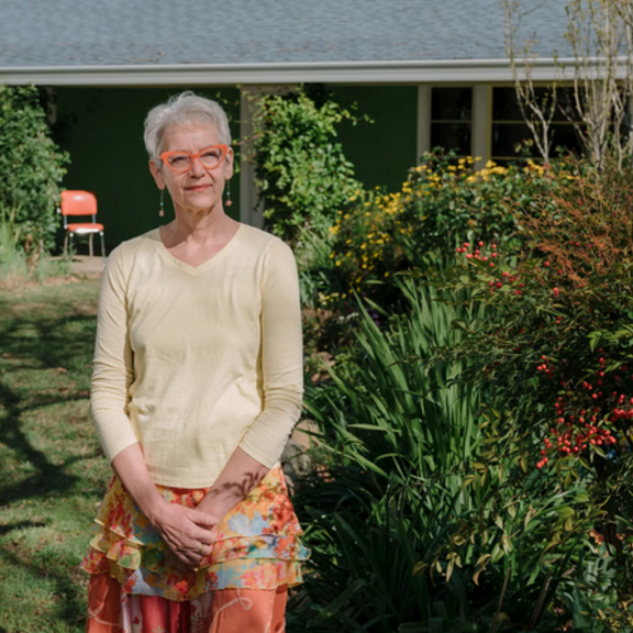 Older woman standing in front of her home.