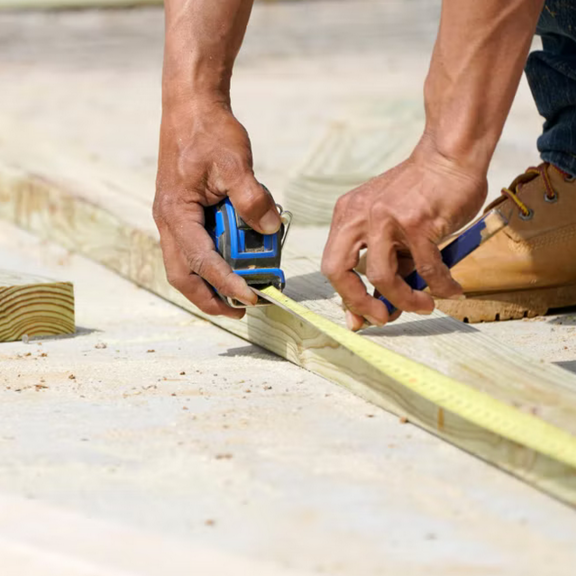 Person using measuring tape on wood beam.