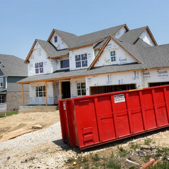 House under construction with dumpster in front.