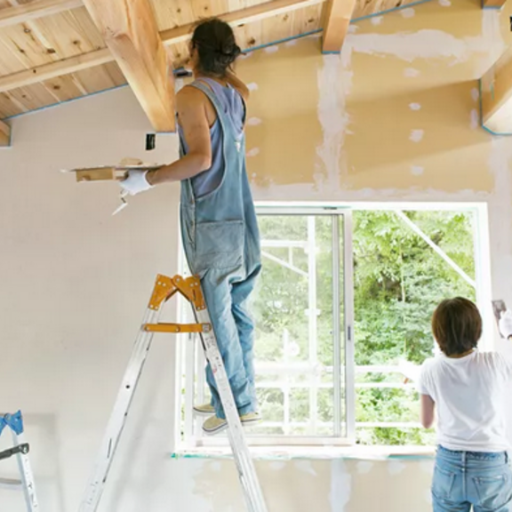 Two people painting interior walls of a house.