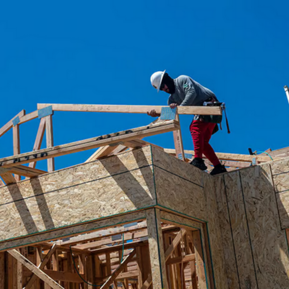 Construction workers on top of partially-built home.