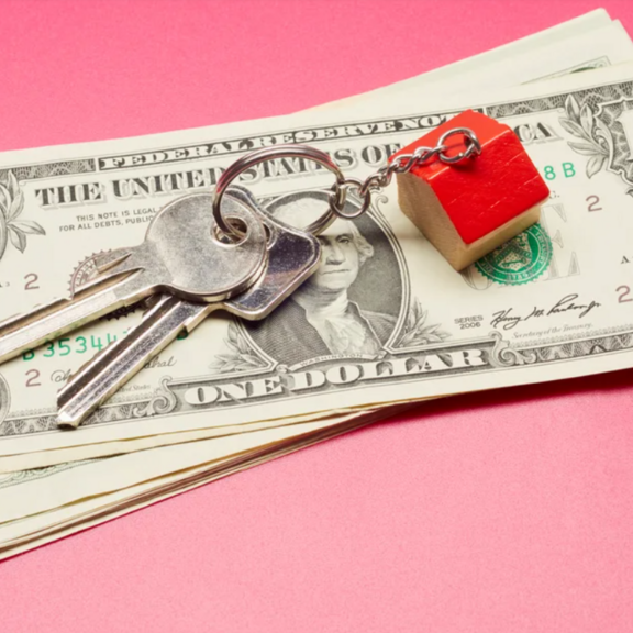 House shaped key holder with keys on a stack of one dollar bills