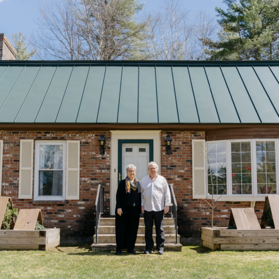 Elderly couple infront of a house