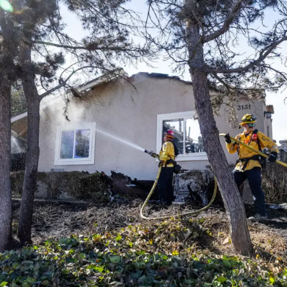 Firefighters with hoses outside a home