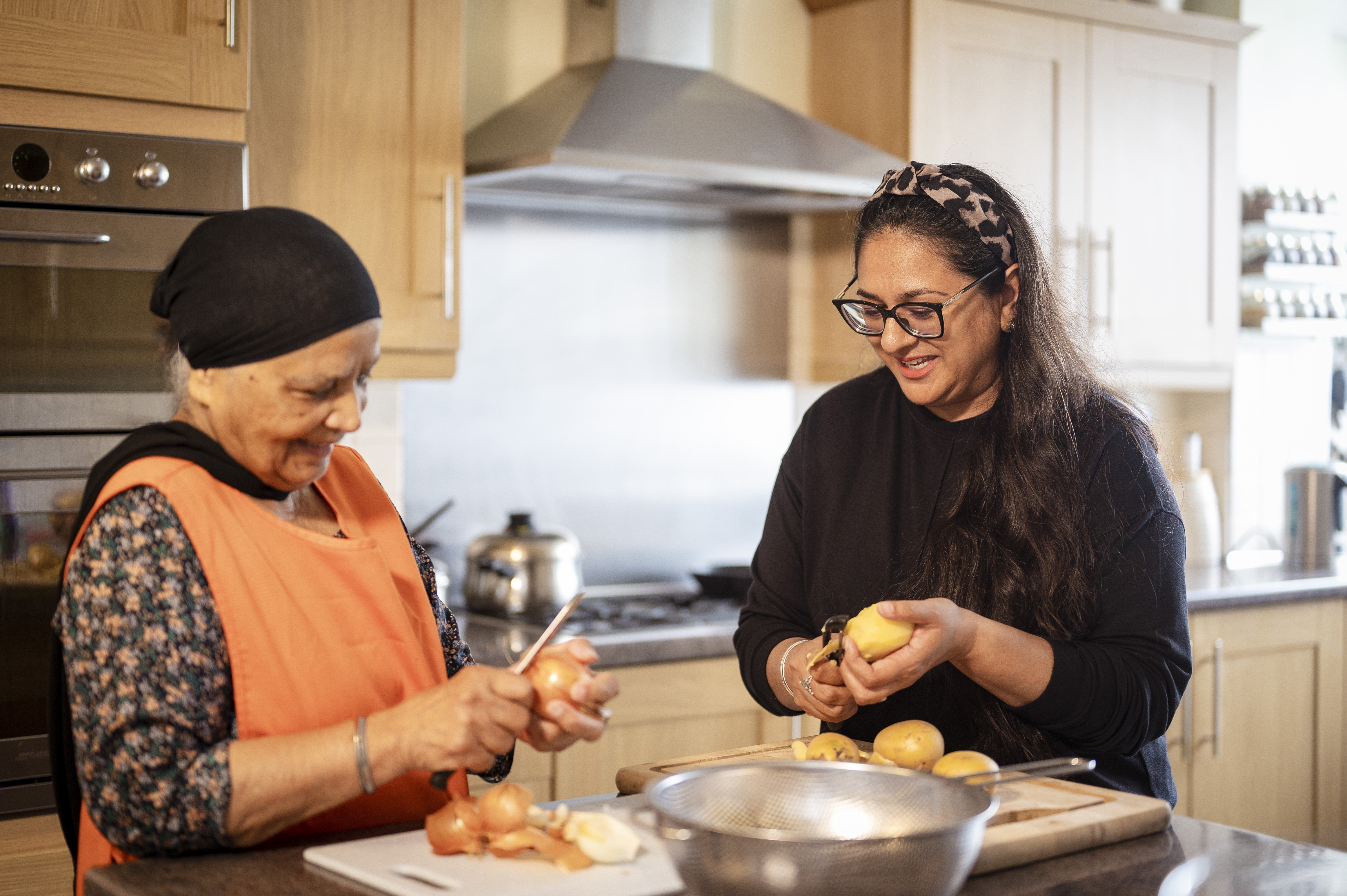 Older and younger woman cooking together in a kitchen.