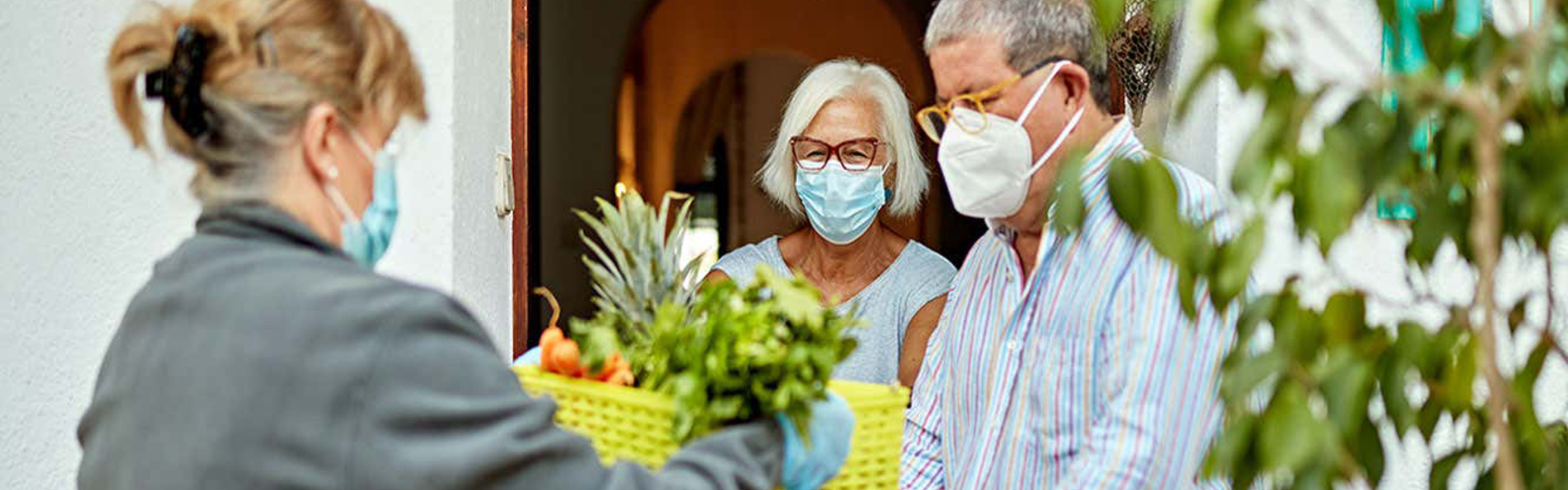 Older adults in face masks receive a grocery delivery