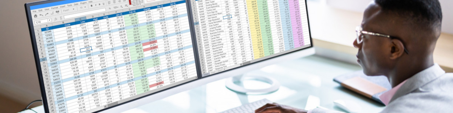 Person looking at 2 monitors of spreadsheets