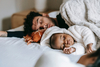 Father and baby napping on bed.