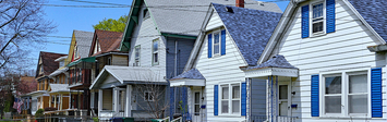 Row of small wooden houses with front yards.