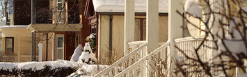 Snowy front porch and houses in the background.