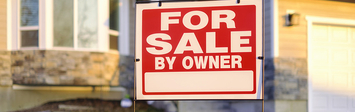 For-sale sign in yard of small home.