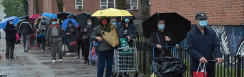 New Yorkers line up in the rain with carts and umbrellas.