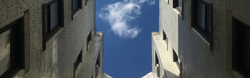View of the sky looking up through the courtyard of an apartment building.